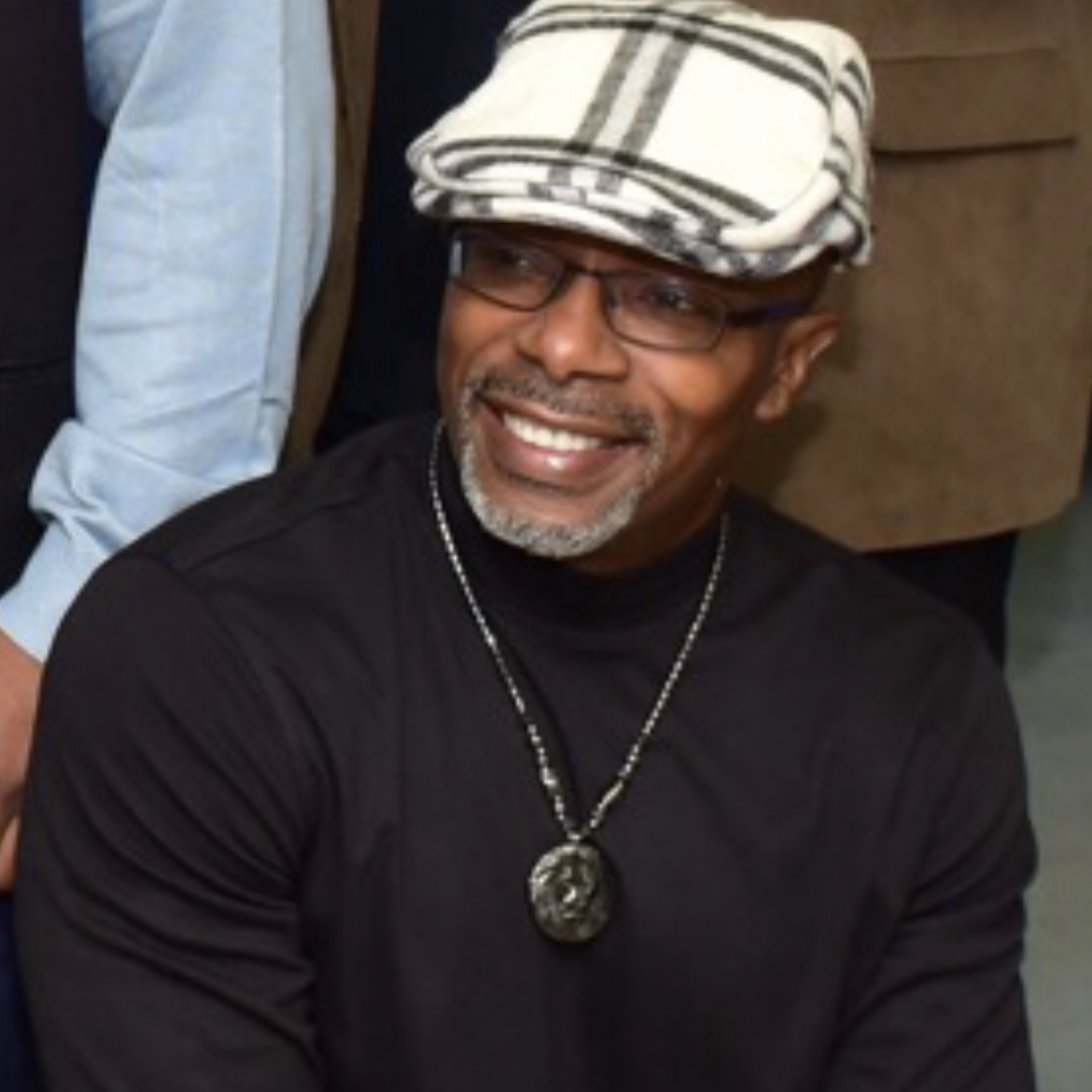 Darrell Siggers smiling while wearing a checkered cap